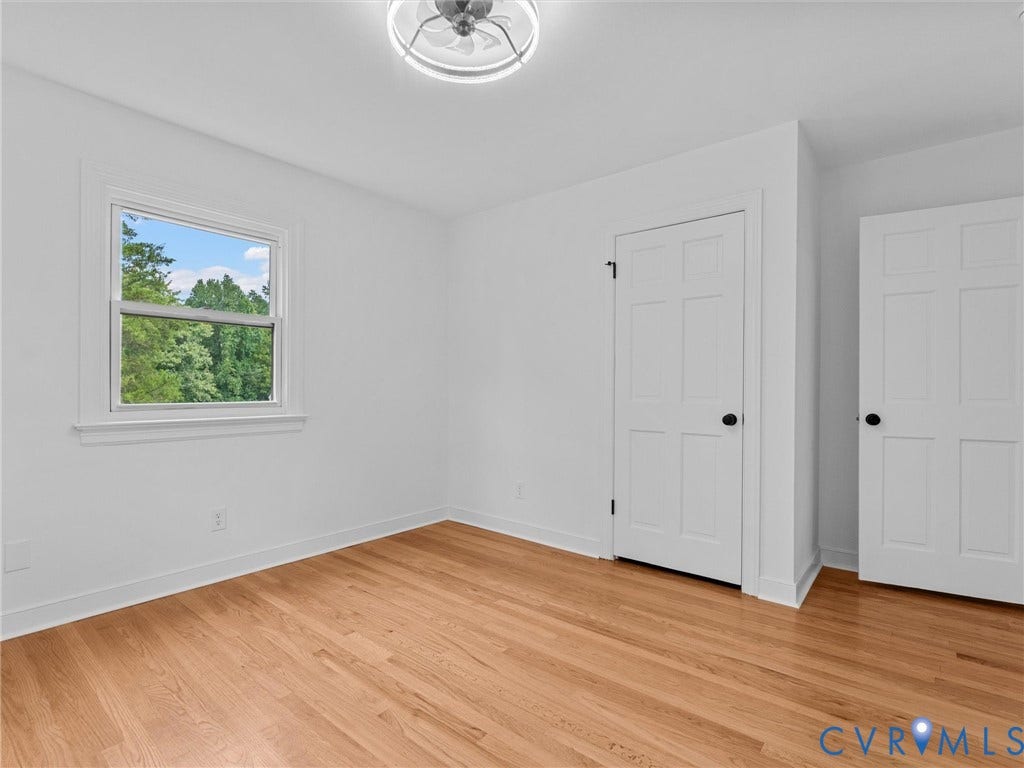 7361 Creekridge Road, Henrico, VA 23231 Light wood-finish flooring, white walls, multiple paneled doors with black hardware, double-hung window with white trim, and a ceiling-mounted light fixture