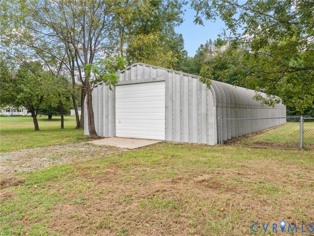 7361 Creekridge Road, Henrico, VA 23231 Metal Quonset hut structure with a white roll-up door, concrete apron, and surrounding grassy area