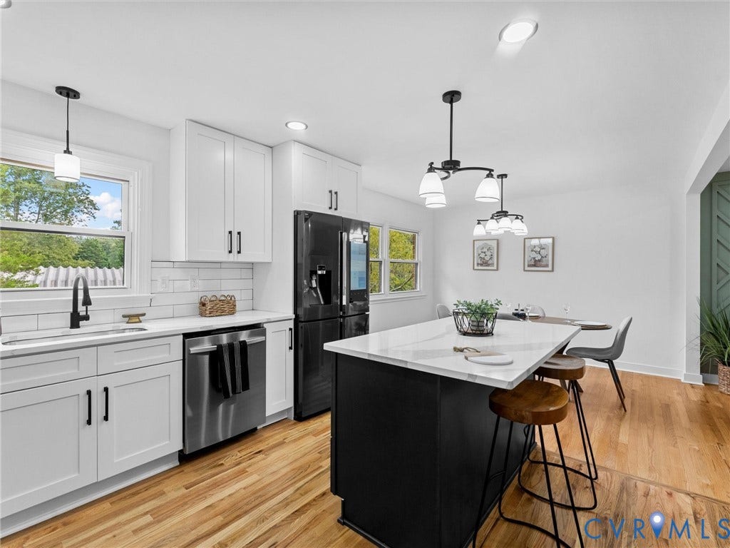 7361 Creekridge Road, Henrico, VA 23231 Kitchen featuring white cabinetry, a black kitchen island with a light-toned countertop, stainless steel dishwasher, a black refrigerator, and wood-finish flooring