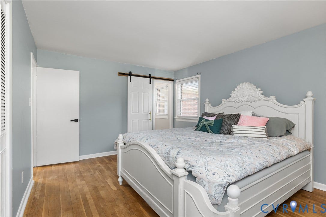 300 Gunby Drive, Henrico, VA 23229 Wood-finish flooring, light blue wall paint, white trim, and a white barn door on a black track