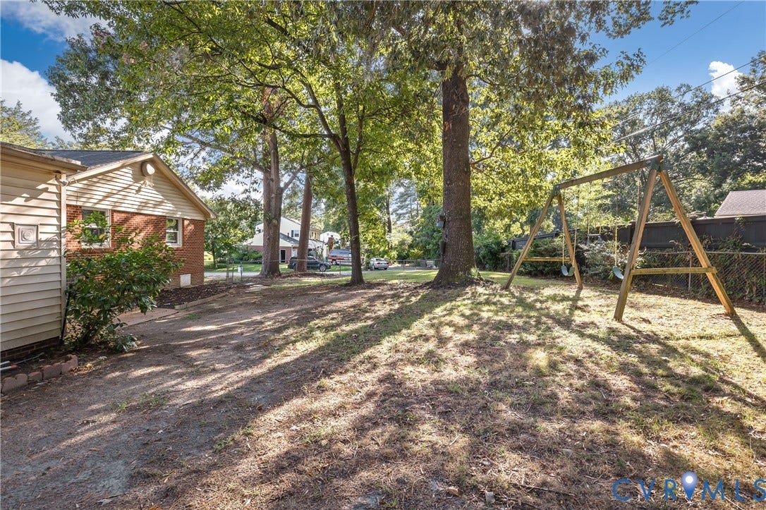 300 Gunby Drive, Henrico, VA 23229 Expansive rear yard featuring mature trees, a wooden swing set, and a partial chain-link fence