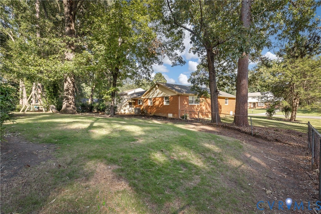 300 Gunby Drive, Henrico, VA 23229 Expansive green space with mature trees, a brick-clad exterior, and a chain-link fence