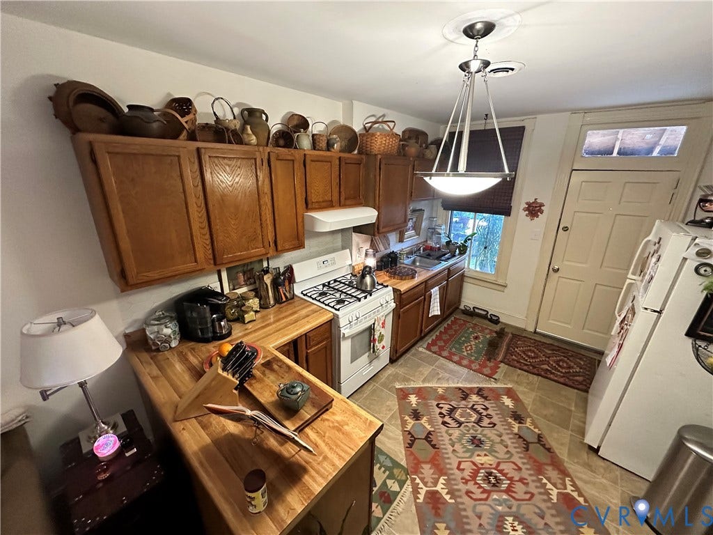 Kitchen featuring wood-finish cabinetry, solid surface countertops, a gas range, and tile flooring