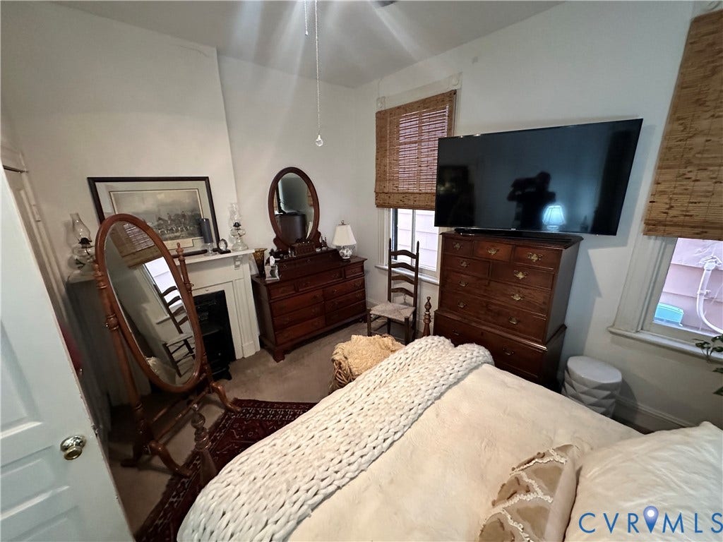 Fireplace with a classic mantel, ceiling fan, and window with woven blinds
