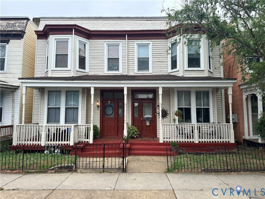 Dual-entry facade with two bay windows and a covered front porch featuring white railings