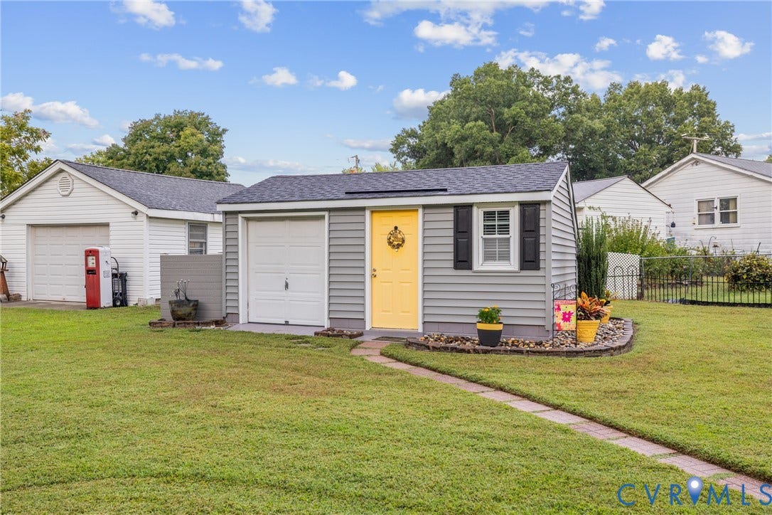 822 Old Town Drive, Colonial Heights, VA 23834 Detached structure featuring a single garage door, a vibrant yellow entry door, exterior siding, and a window with dark shutters