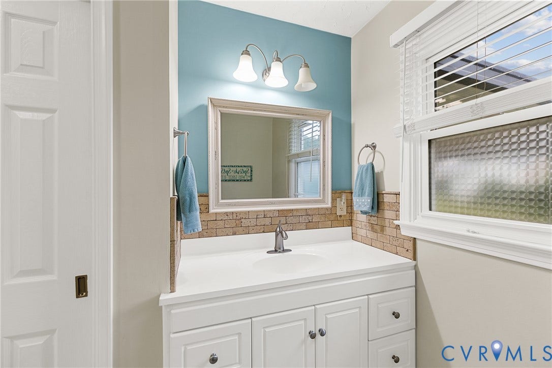 822 Old Town Drive, Colonial Heights, VA 23834 White vanity with an integrated sink and brushed nickel faucet, framed mirror, and a three-light vanity fixture