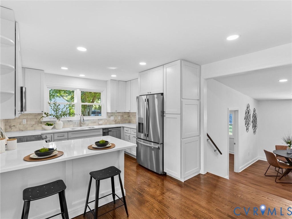 Kitchen featuring white shaker cabinetry, stainless steel appliances, light-toned countertops, and a subway tile backsplash