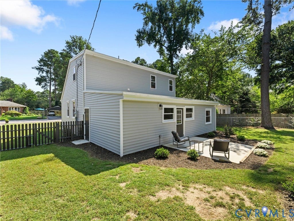 Backyard with a concrete patio, light gray siding, and a white picket fence
