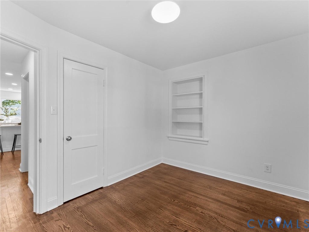 Wood-finish flooring, built-in shelving, white walls, and a flush-mount ceiling light