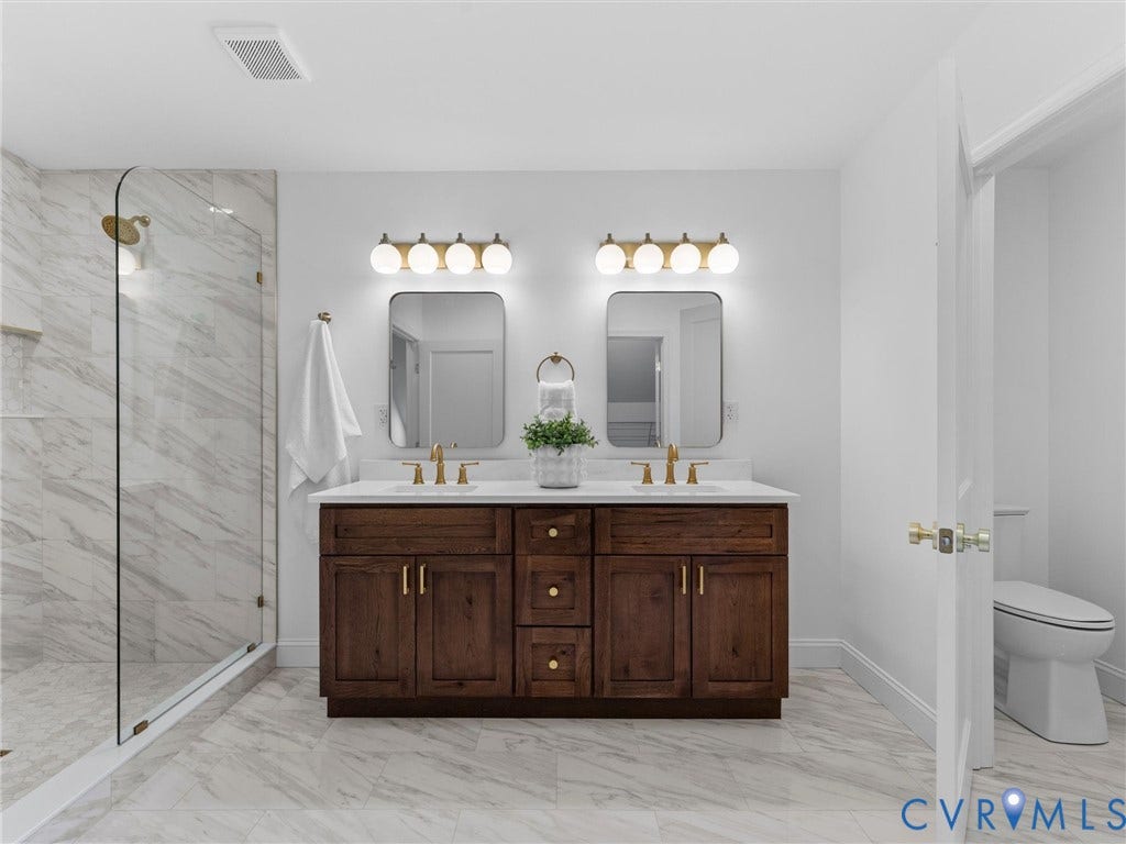 Dual vanity with dark wood-finish cabinetry, white countertop, and gold-finish fixtures