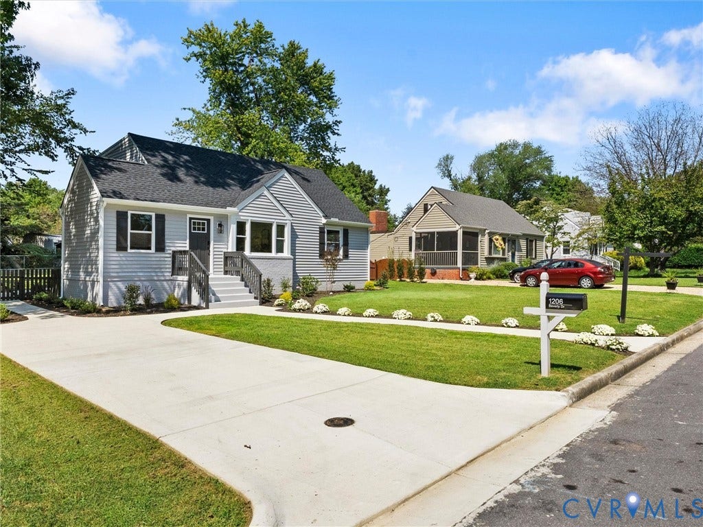 Light gray siding exterior with black shutters, a dark gray front door, and a concrete driveway