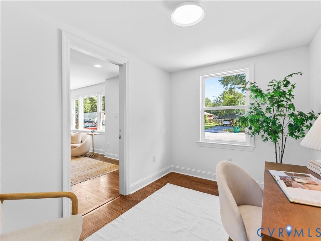 Hardwood flooring, painted white walls, white window trim, and a flush mount ceiling light