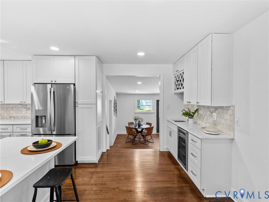 Hardwood flooring, stainless steel refrigerator, white cabinetry, integrated wine cooler, and light-toned backsplash