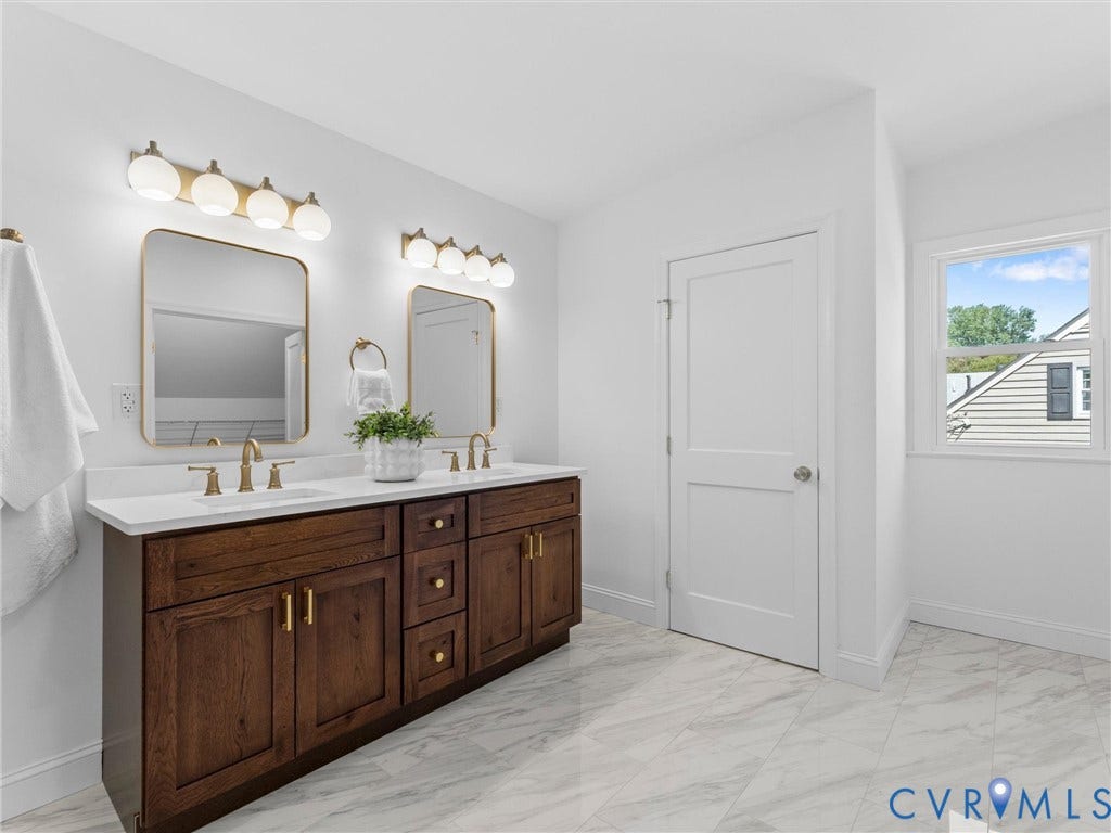 Double vanity with dark wood-finish cabinetry, white countertop, and gold-finish fixtures