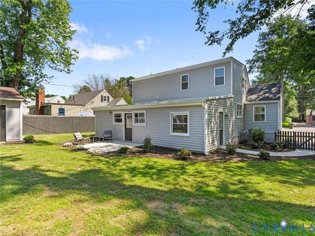 Expansive backyard with a manicured lawn, concrete patio, and a storage shed