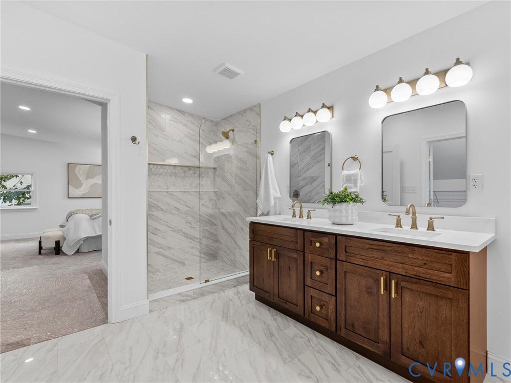 Dual vanity with wood-finish cabinetry, white countertops, and gold-tone hardware