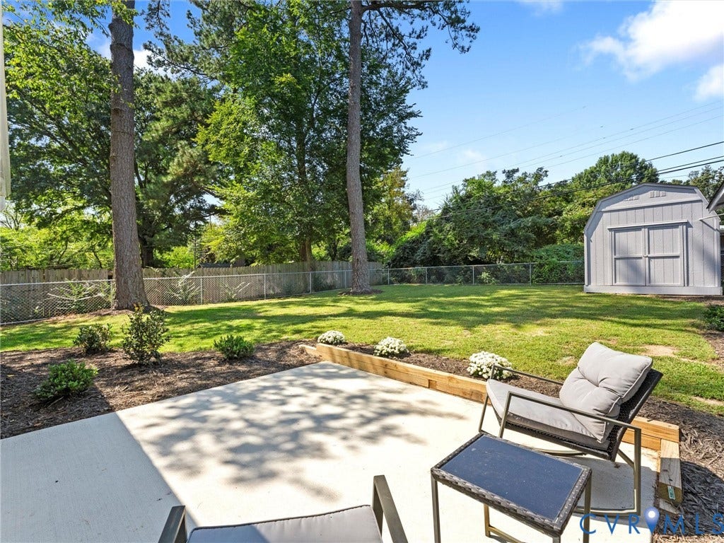 Concrete patio, manicured lawn, established trees, privacy fencing, and storage shed