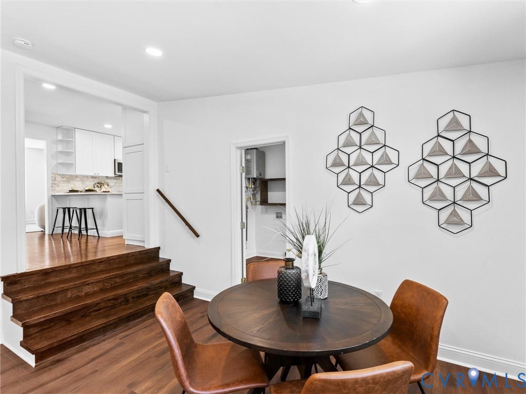 Rich wood-finish flooring, staircase with a wood handrail, and crisp white walls