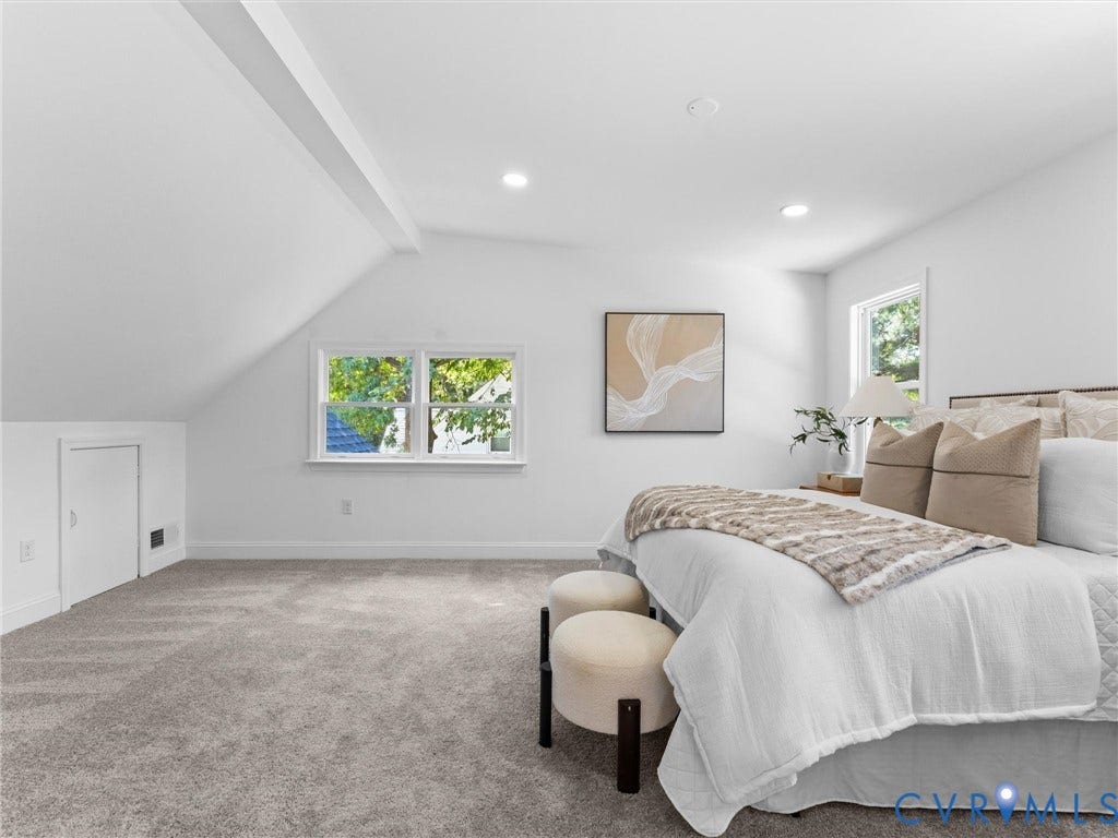Vaulted ceiling with exposed beam, recessed lighting, double window, plush carpet, and a built-in access door