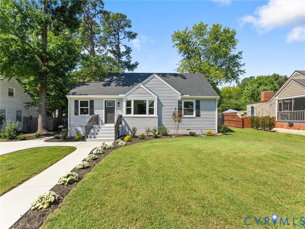Light gray siding exterior with a dark gray shingle roof, featuring a gabled dormer and black shutters