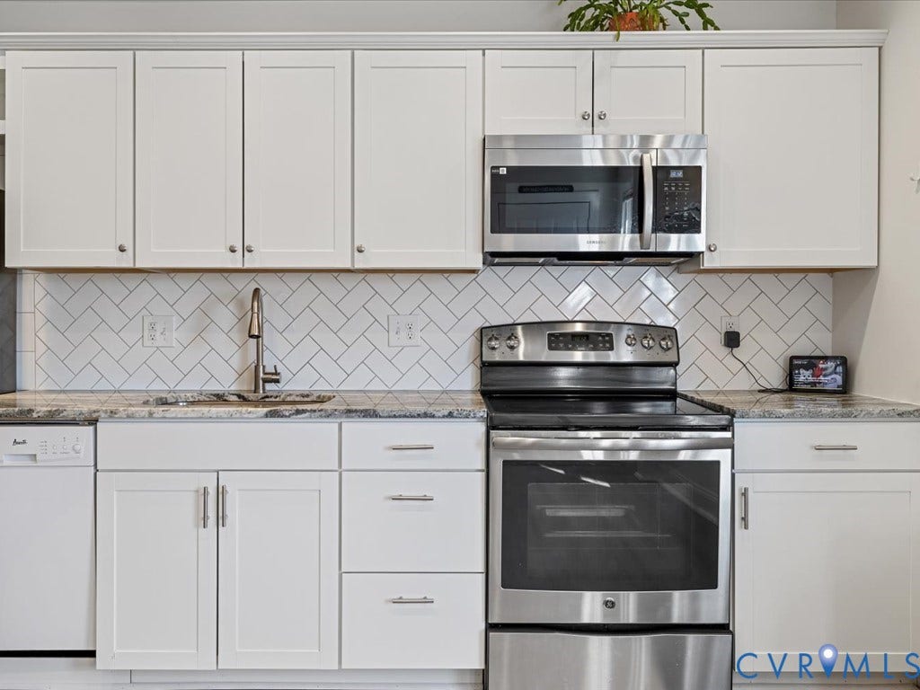 2021 Venable Street, Union Hill, Richmond, VA 23223 White shaker-style cabinetry with crown molding, stainless steel appliances, herringbone tile backsplash, undermount sink with a pull-down faucet, and speckled countertops