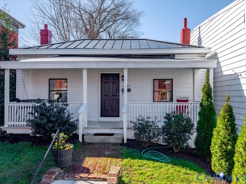 2021 Venable Street, Union Hill, Richmond, VA 23223 White siding exterior with a dark paneled entry door, covered front porch, white porch railing, and a black metal roof