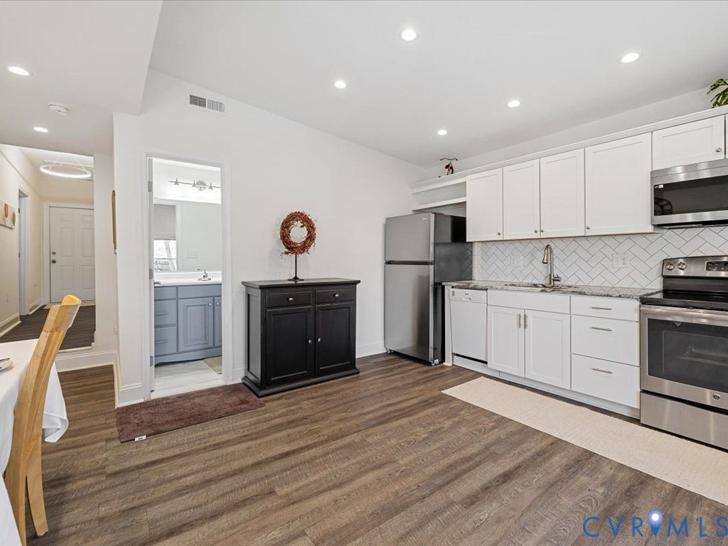 2021 Venable Street, Union Hill, Richmond, VA 23223 Wood-finish flooring throughout, kitchen featuring white cabinetry, stainless steel appliances, and a herringbone tile backsplash