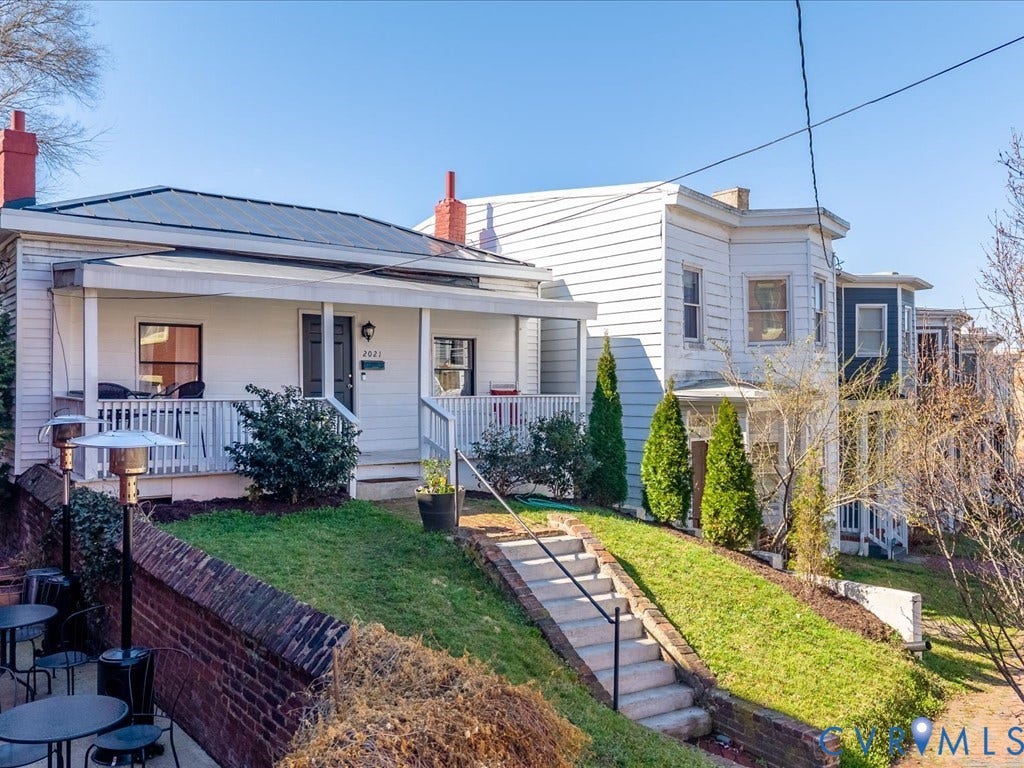 2021 Venable Street, Union Hill, Richmond, VA 23223 White siding exterior with a dark-paneled roof, covered front porch, and red brick chimney