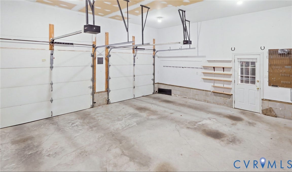 5500 Lakemere Drive, 55+ Community, North Chesterfield, VA 23234 Two overhead garage doors with automatic openers, concrete flooring, overhead lighting, side door access, and wall-mounted shelving