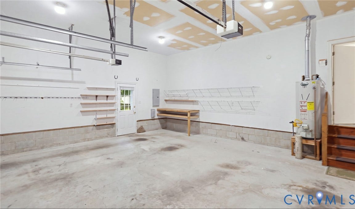5500 Lakemere Drive, 55+ Community, North Chesterfield, VA 23234 Concrete flooring garage with wall-mounted shelving, built-in workbench, and overhead lighting