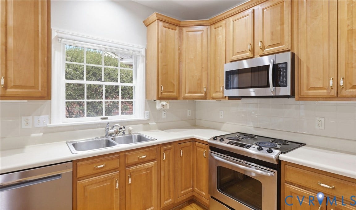 5500 Lakemere Drive, 55+ Community, North Chesterfield, VA 23234 Kitchen featuring wood-finish cabinetry, stainless steel appliances, a double basin sink, and a tiled backsplash