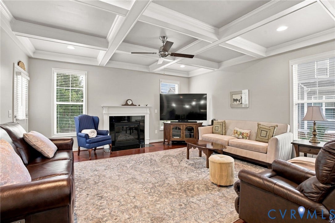 Coffered ceiling with recessed lighting and a ceiling fan, hardwood flooring, and a fireplace with a white mantel