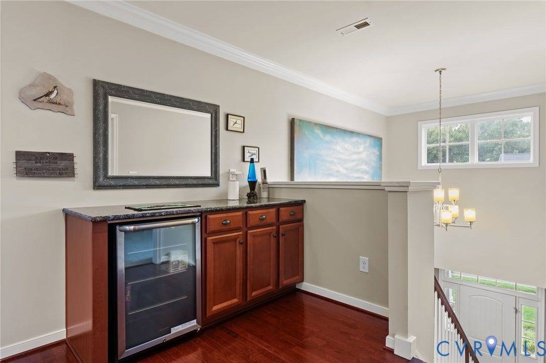 Built-in cabinetry with a stone-finish countertop, under-counter beverage refrigerator, and rich wood-finish flooring
