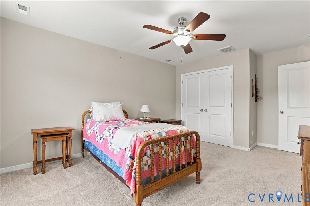 Neutral wall color, carpeted flooring, ceiling fan with light fixture, double-door closet, and an additional white paneled door