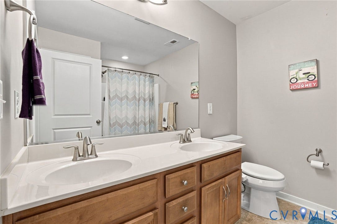 Double vanity with integrated sinks, brushed nickel faucets, wood-finish cabinetry, and a large wall-mounted mirror