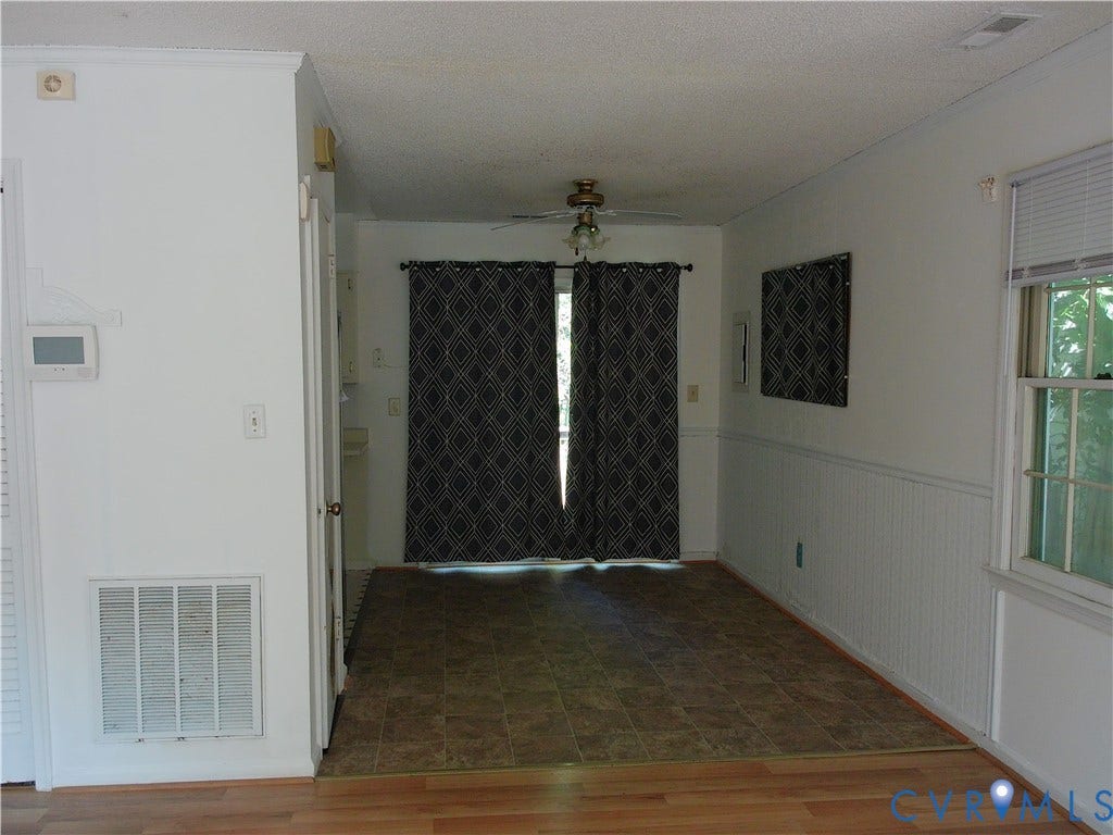Wood-finish flooring, half-wall wainscoting, and a ceiling fan with integrated lighting