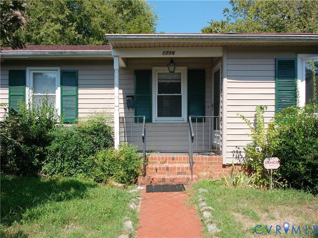 Front entry with brick steps, a covered porch, and white column