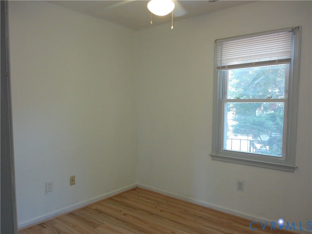 Wood-finish flooring with white baseboards, single window with blinds, and ceiling-mounted light fixture