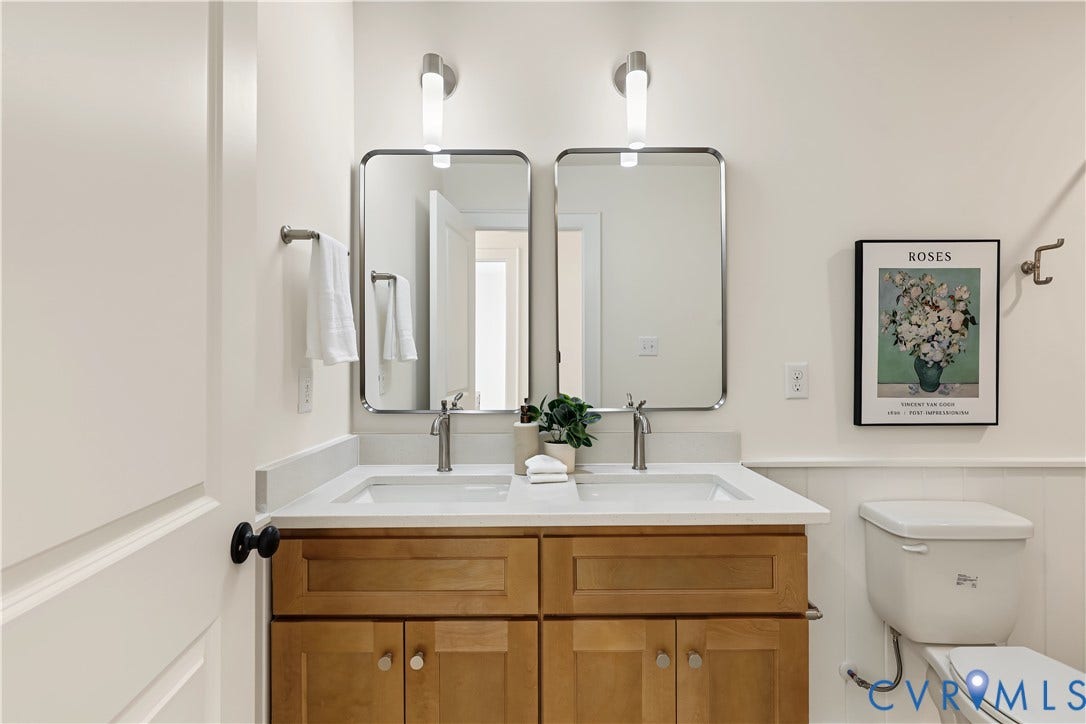 702 Westham Parkway, Westham, Henrico, VA 23229 Dual vanity with light wood-finish cabinetry, integrated sinks, brushed nickel faucets, and coordinating wall-mounted light fixtures