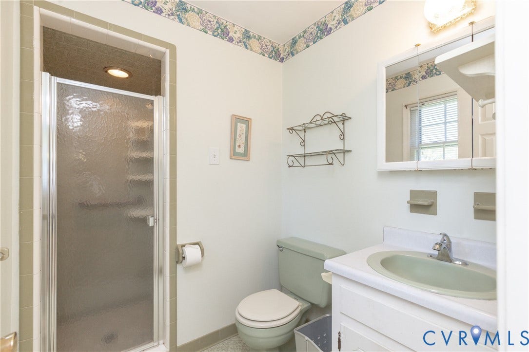 3640 Kiefer Road, Chester, VA 23831 Bathroom featuring a vanity with an integrated sink, a framed medicine cabinet, a toilet, a shower stall with a textured glass door, and tiled walls
