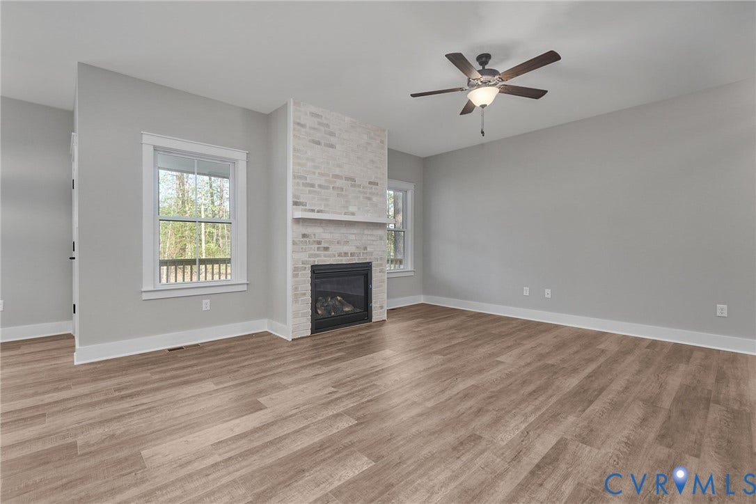 11121 Somerset Hill Drive, Somerset Hills, Glen Allen, VA 23059 Spacious room featuring wood-finish flooring, a contemporary ceiling fan, and a fireplace with a white brick surround