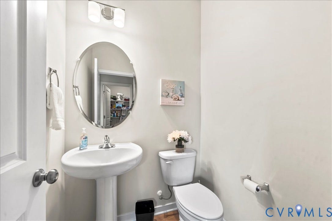412 Quiet Breeze Alley, Chesterfield, VA 23113 Pedestal sink with a polished chrome faucet, oval wall mirror, and modern wall-mounted lighting