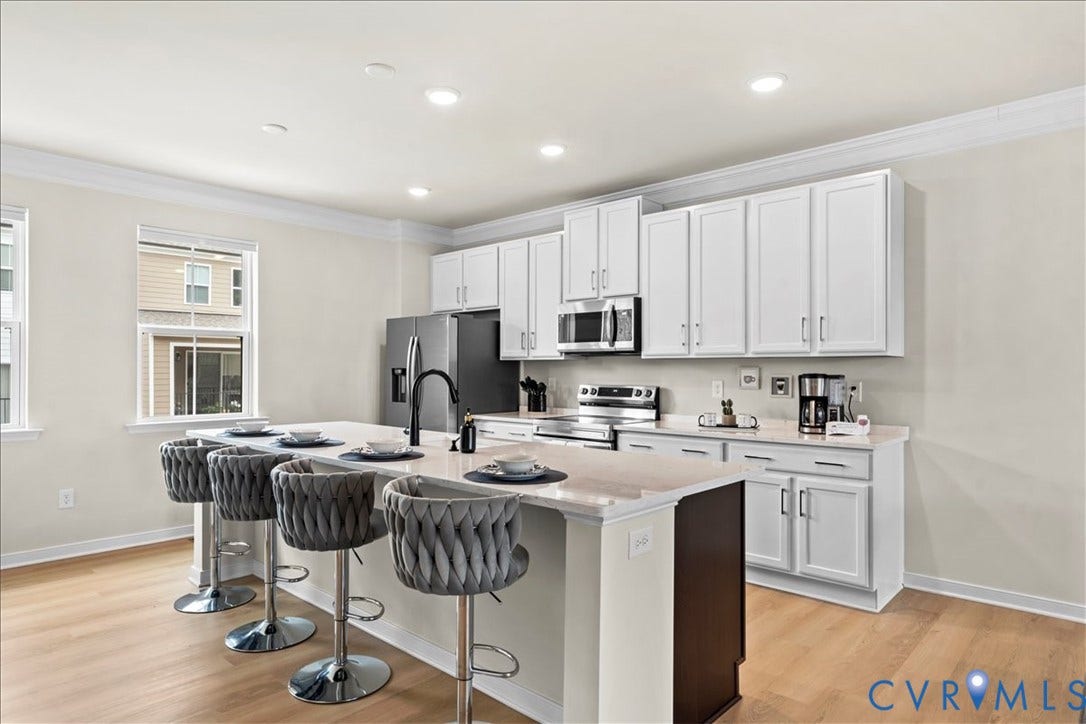 412 Quiet Breeze Alley, Chesterfield, VA 23113 Kitchen featuring an island with counter seating, white cabinetry, stainless steel appliances, and light wood-finish flooring