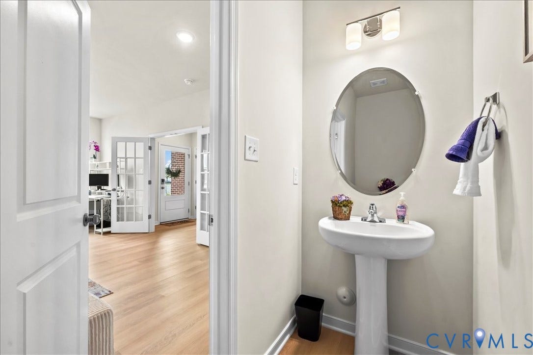 412 Quiet Breeze Alley, Chesterfield, VA 23113 Pedestal sink with chrome faucet, oval mirror, and wall-mounted light fixture