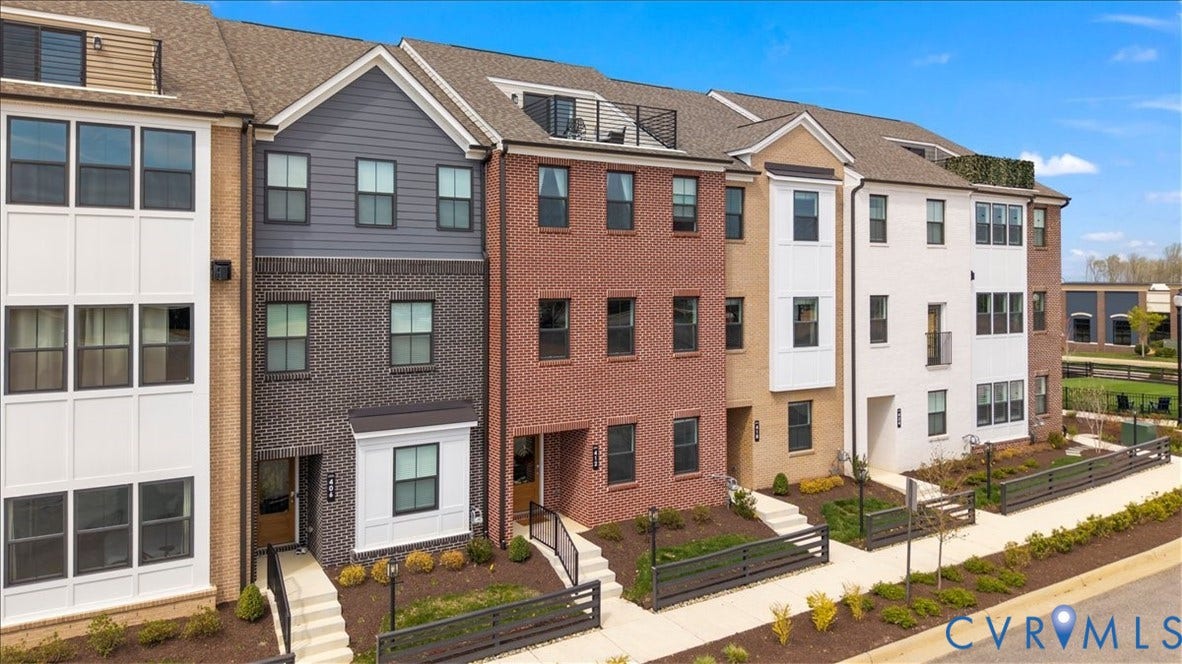 412 Quiet Breeze Alley, Chesterfield, VA 23113 Multi-story townhome with brick and siding facade, featuring multiple windows, sloped rooftops, and front entryways with exterior lighting