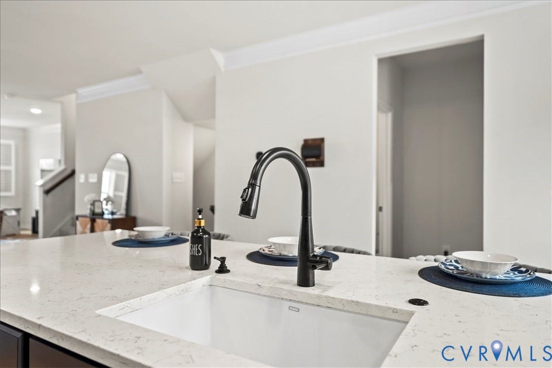 412 Quiet Breeze Alley, Chesterfield, VA 23113 Kitchen island featuring an integrated sink with a matte black gooseneck faucet, light-toned countertop, and crown molding