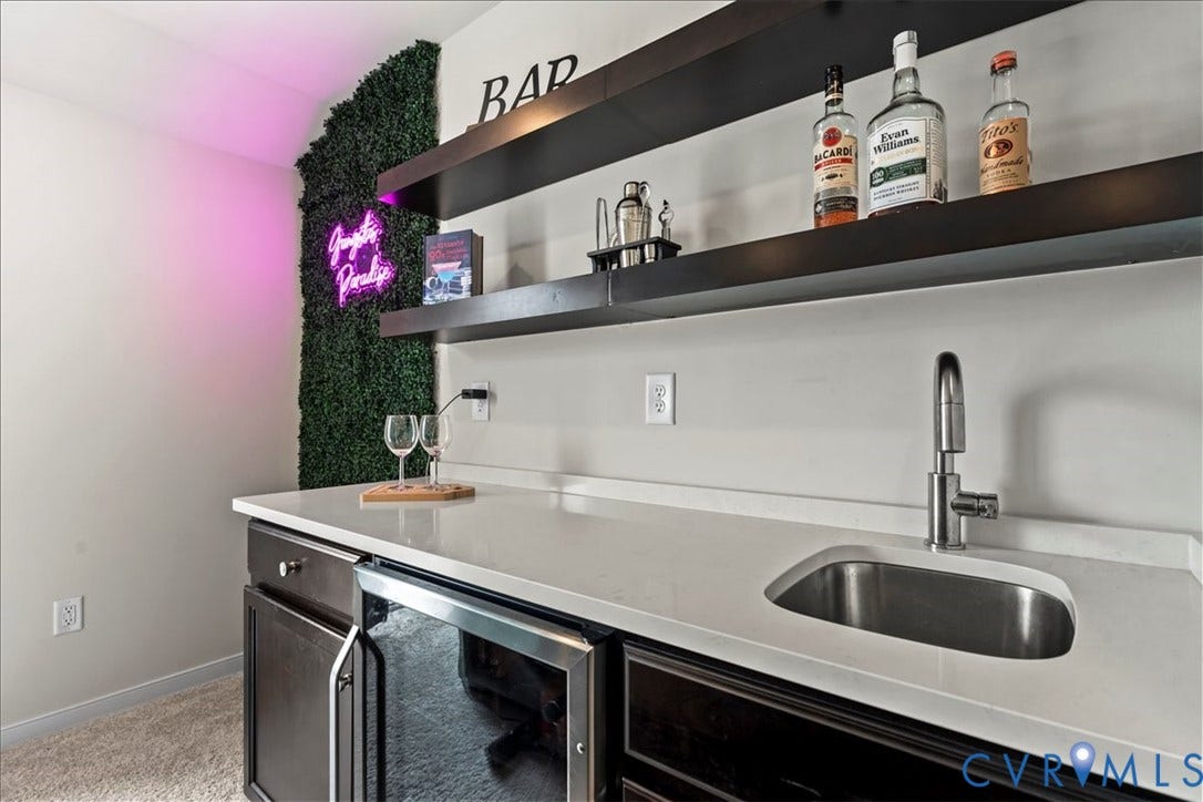 412 Quiet Breeze Alley, Chesterfield, VA 23113 Built-in wet bar featuring dark wood-finish cabinetry, a beverage refrigerator, light-toned countertop, and undermount sink with a gooseneck faucet