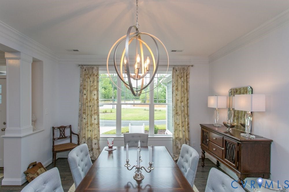 Formal dining space with a contemporary chandelier, crown molding, and wood-finish flooring