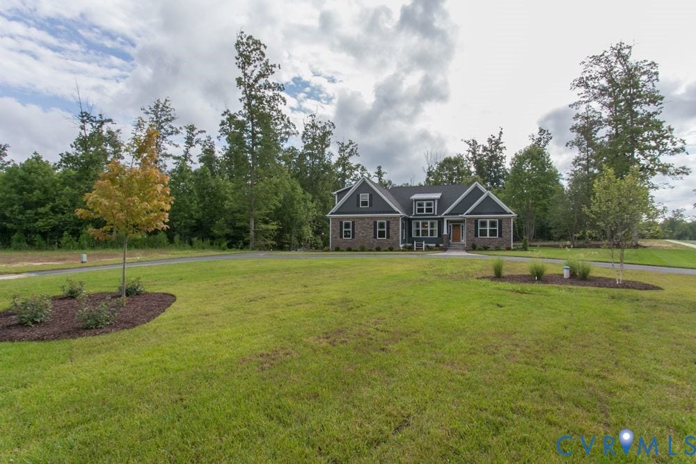 Expansive manicured lawn with mature trees, a paved driveway, and established landscaping
